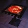 Tavolo con struttura in ferro nero e piano in resina con scarti metallici in intrusione.